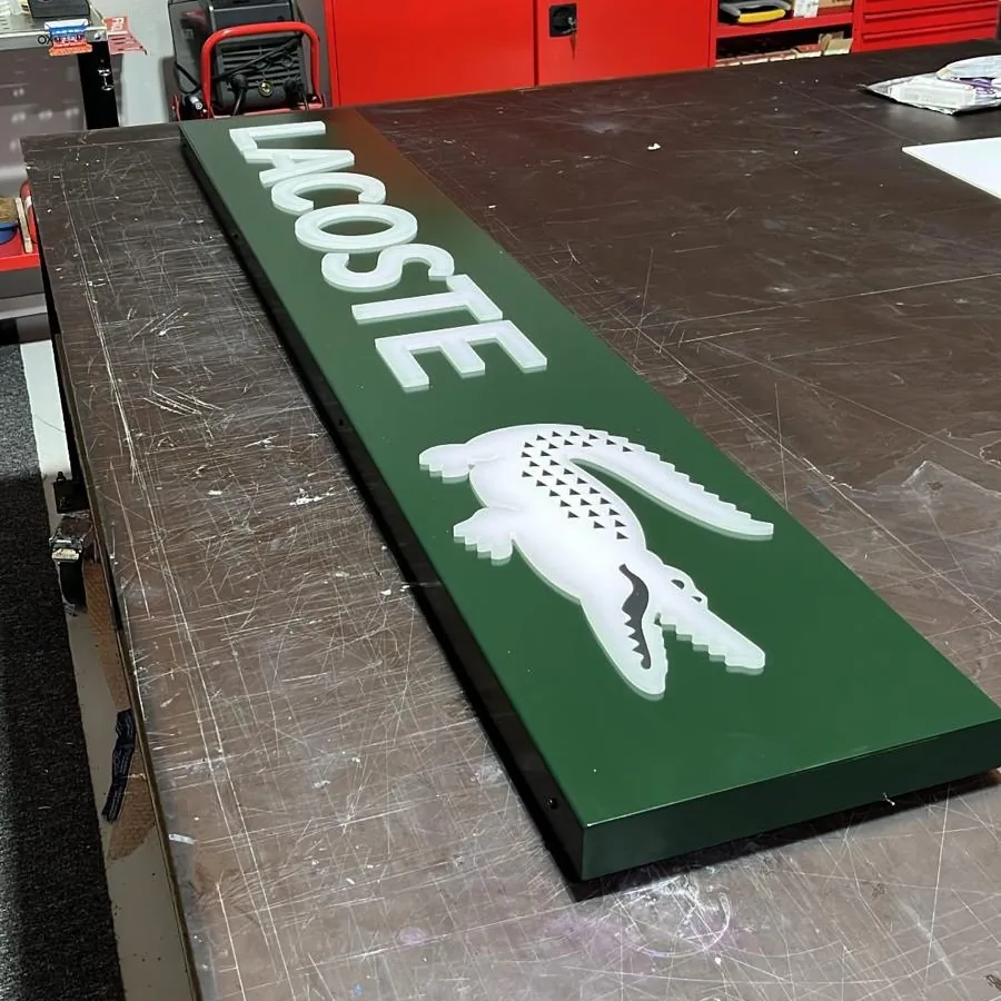 Enseigne caisson lumineux Lacoste — lettres en relief sur fond vert